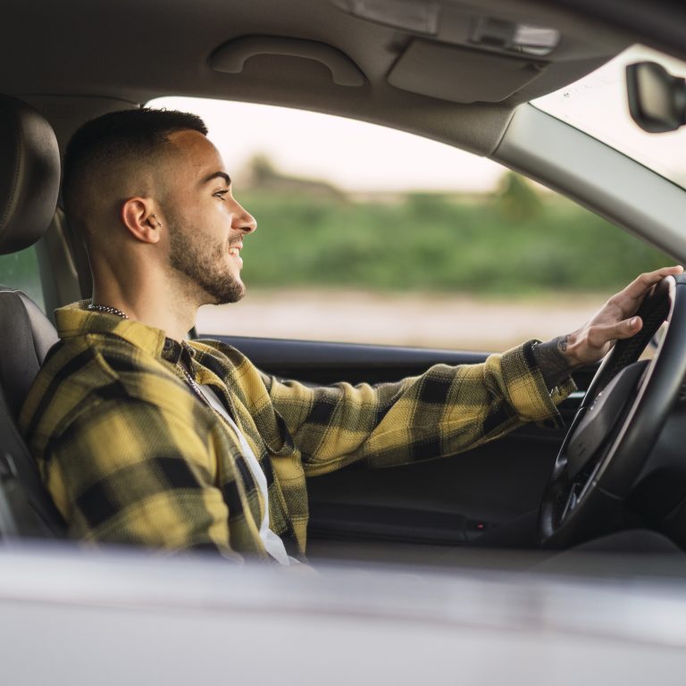 A shallow focus shot of a handsome Spanish Caucasian man sitting behind the wheel of a modern car